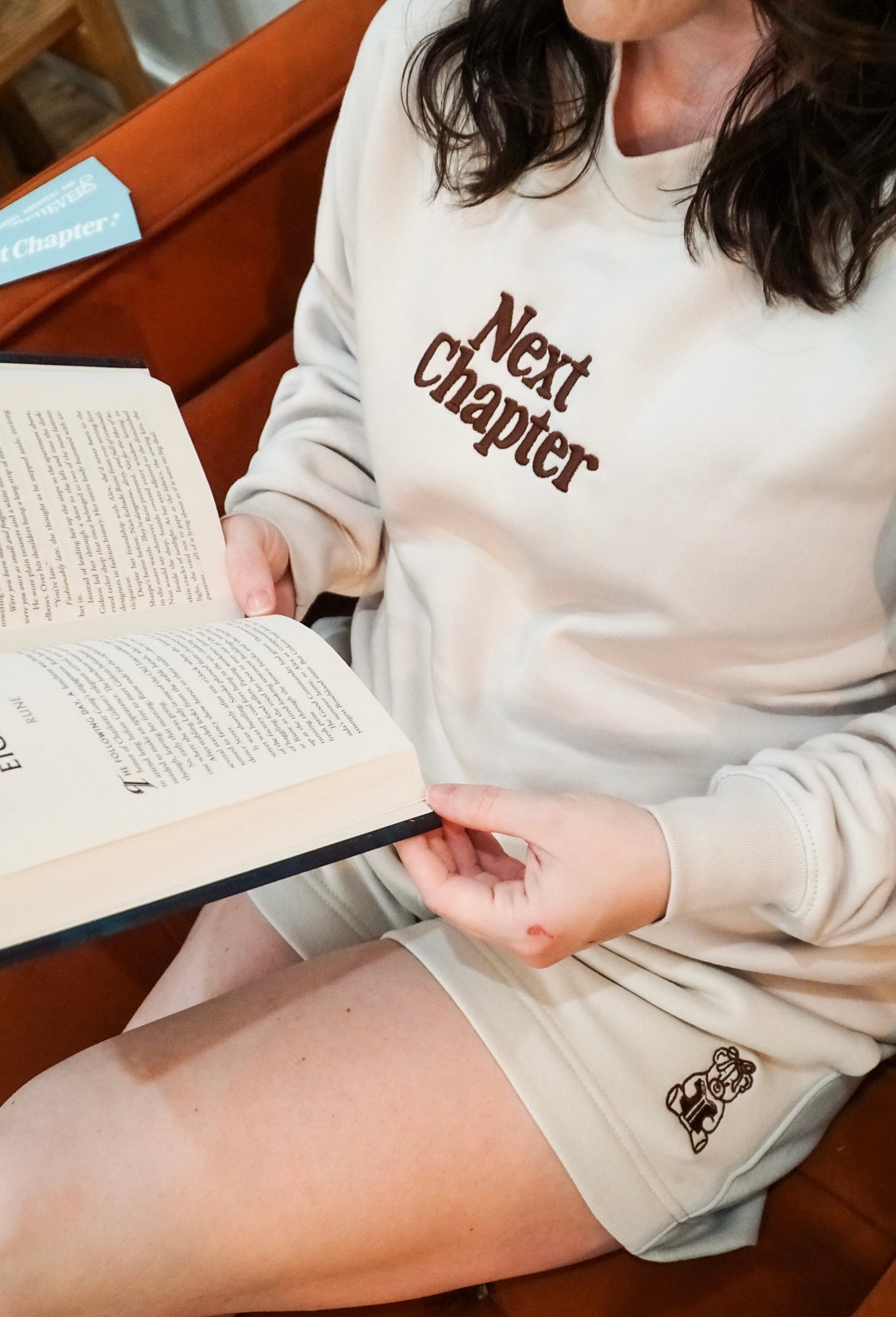 Ivory Book Bear Shorts with embroidered bear detail, elastic waistband, and cozy relaxed fit worn with matching Next Chapter Crewneck pullover.