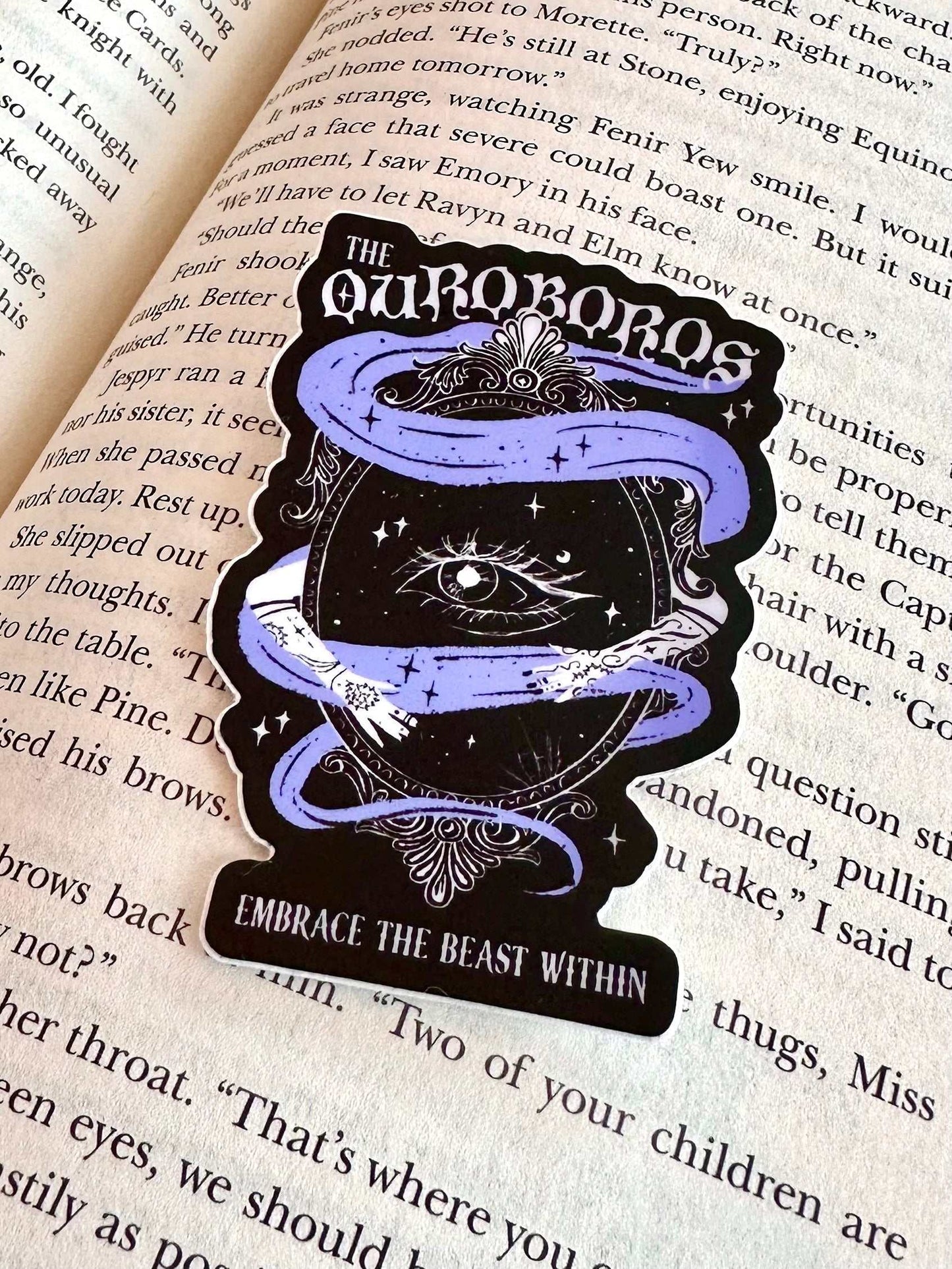 Ouroboros Acotar Sticker featuring a purple ouroboros snake around an eye with "Embrace the beast within" text on a book background