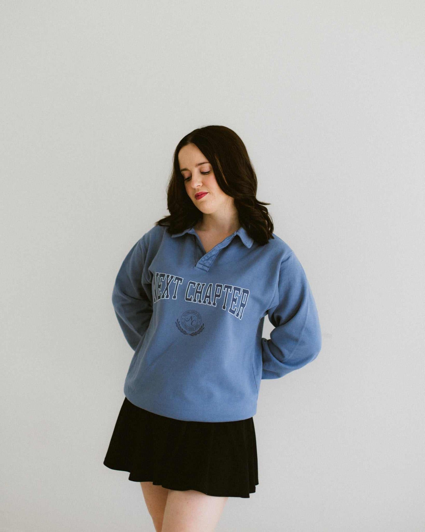 Woman wearing a slate blue Next Chapter collared pullover with navy and white print and a relaxed fit