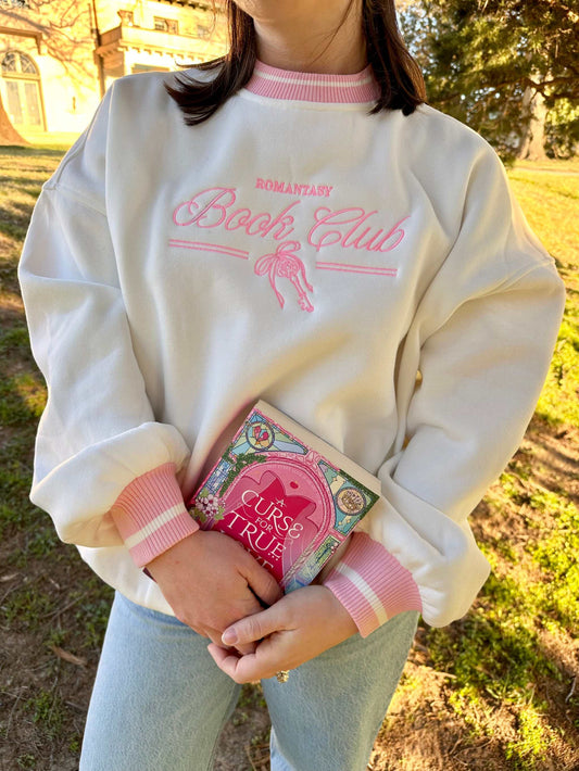 Romantasy Book Club Crewneck. Embroidered sweatshirt with a stylish pink trim collar and sleeves. Book merch for lovers of the romance and fantasy bookish genres.