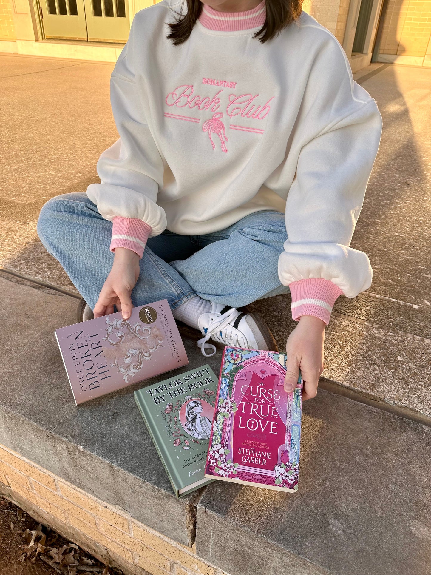Romantasy Book Club Crewneck. Embroidered sweatshirt with a stylish pink trim collar and sleeves. Book merch for lovers of the romance and fantasy bookish genres.
