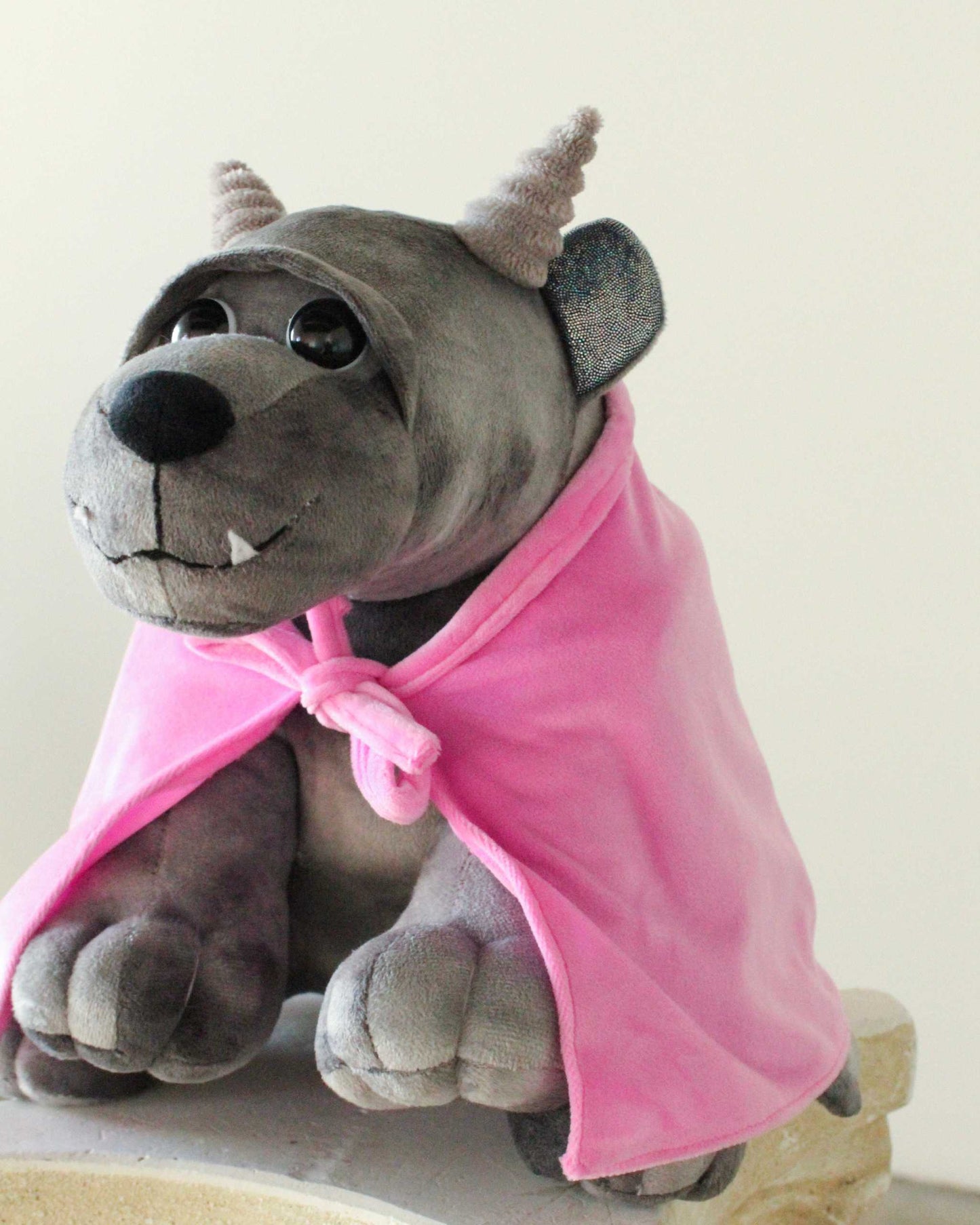 Bartholomew Gargoyle plush with gray soft fabric, small horns, toothy smile, and a bright pink removable cloak