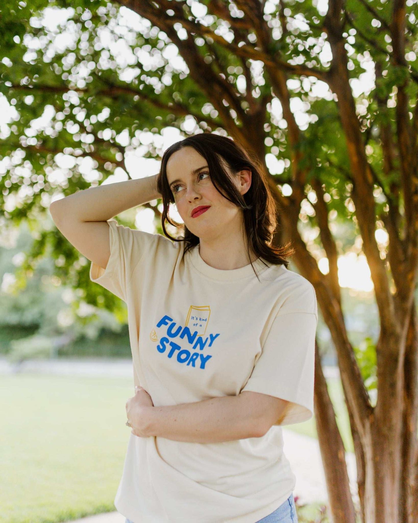 An oversized, boxy t-shirt, the Funny Story Tee is inspired by the book Funny Story by Emily Henry. The item is an ivory/cream color with a royal blue and gold design on the front and back.