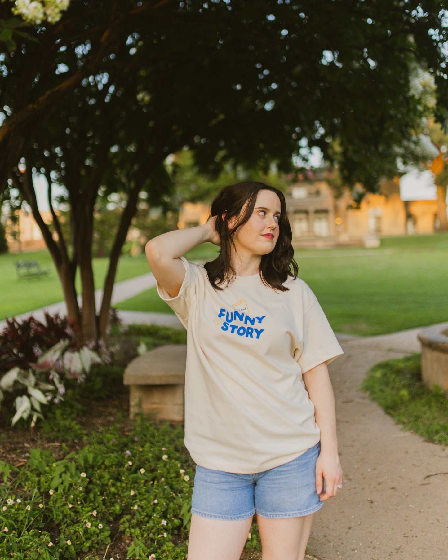 An oversized, boxy t-shirt, the Funny Story Tee is inspired by the book Funny Story by Emily Henry. The item is an ivory/cream color with a royal blue and gold design on the front and back.