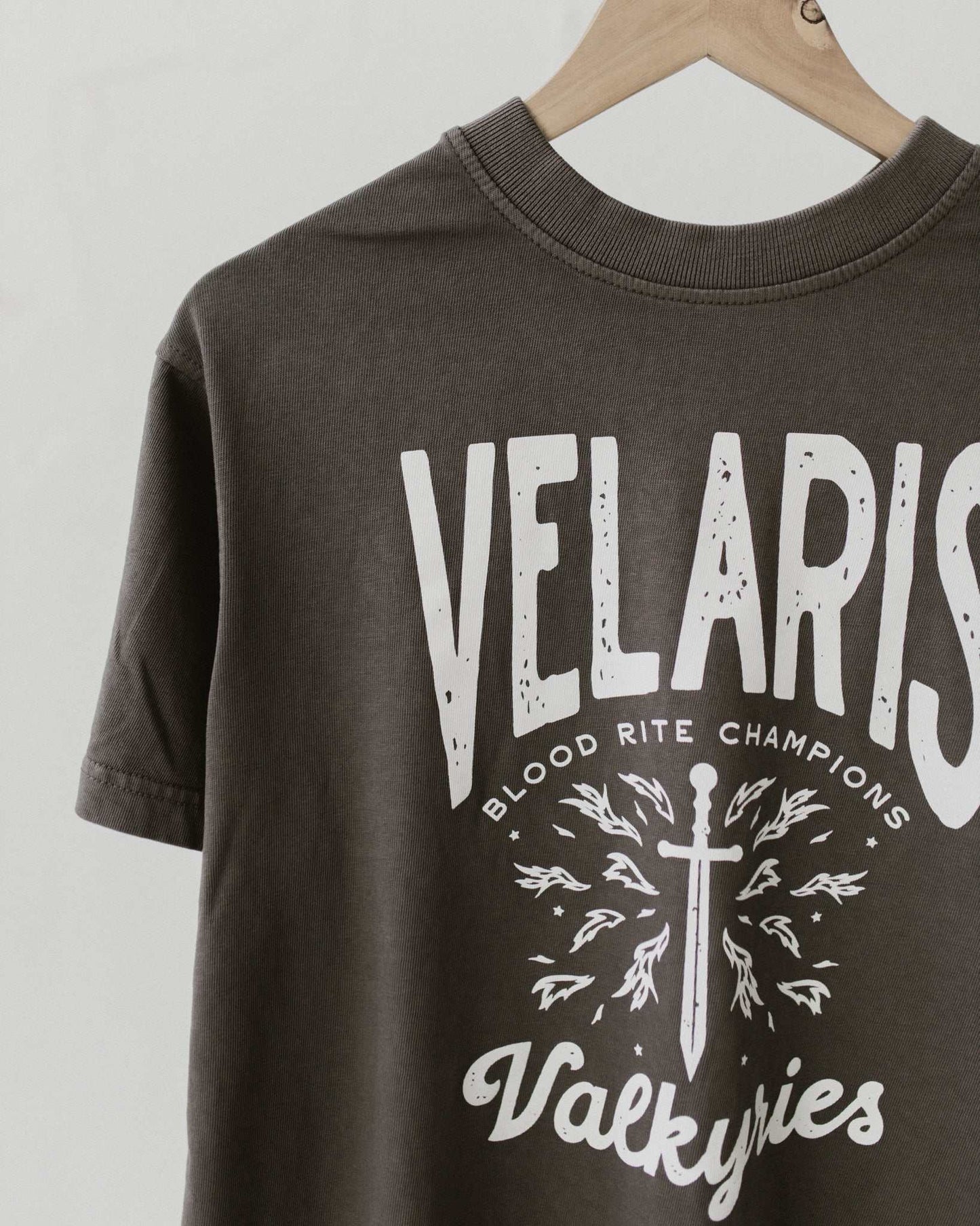 Velaris Valkyries tee featuring a dark gray fabric and white, screen printed design. From A Court of Silver Flames. Officially licensed by Sarah J. Maas.