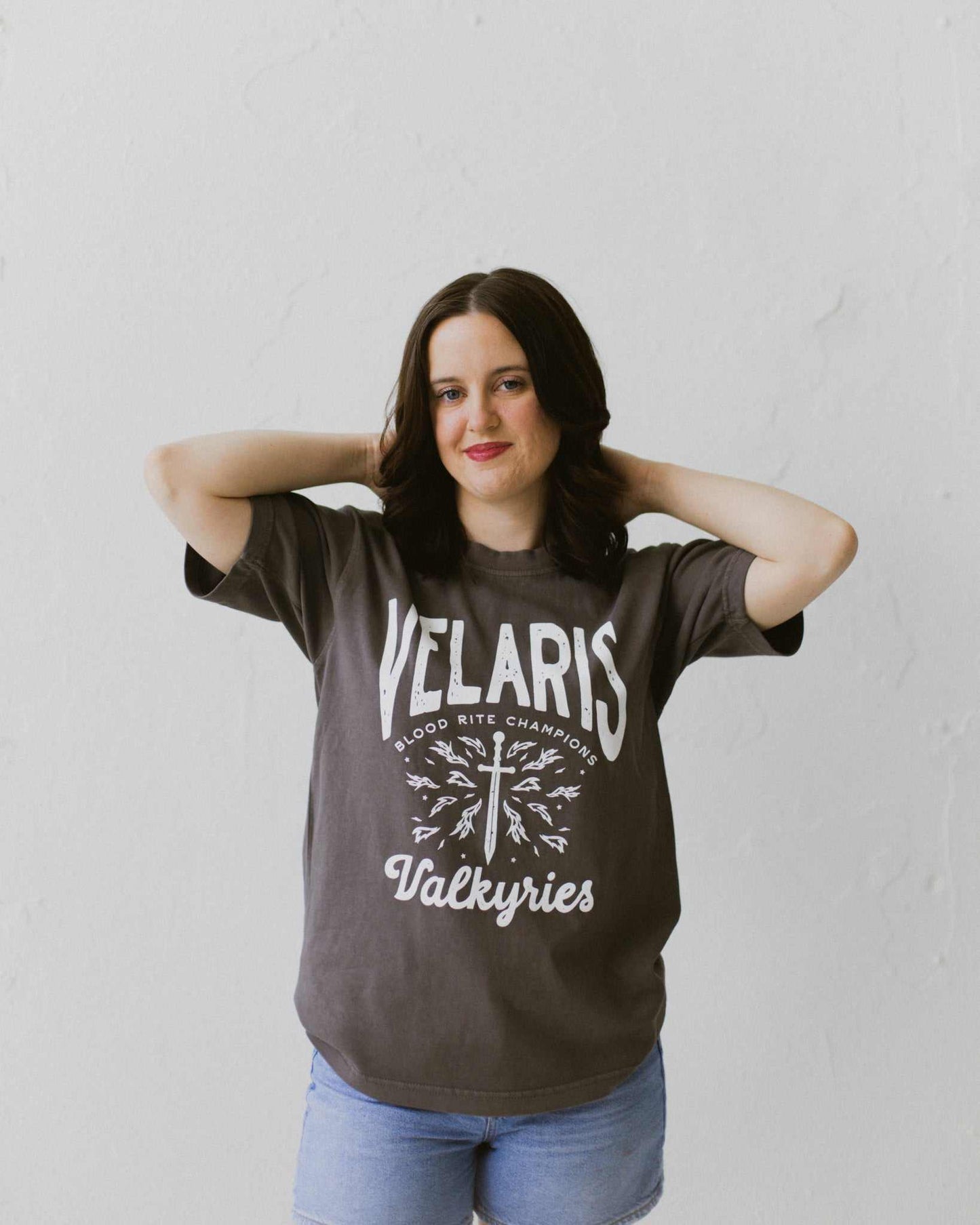 Velaris Valkyries tee featuring a dark gray fabric and white, screen printed design. From A Court of Silver Flames. Officially licensed by Sarah J. Maas.