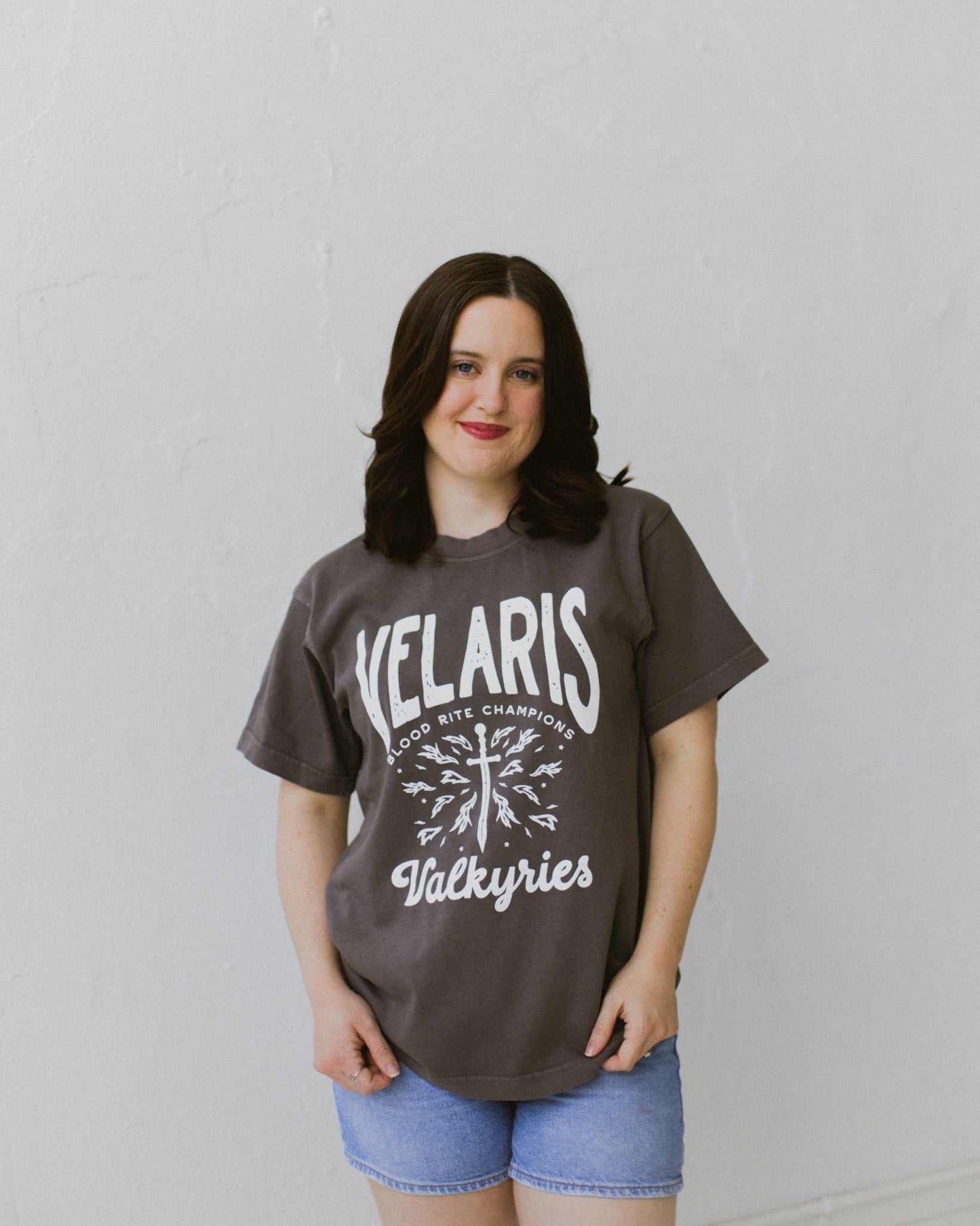 Velaris Valkyries tee featuring a dark gray fabric and white, screen printed design. From A Court of Silver Flames. Officially licensed by Sarah J. Maas.