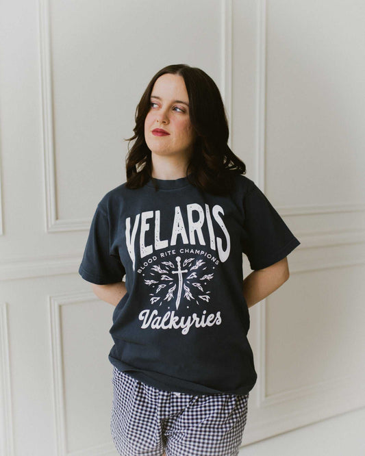 Velaris Valkyries tee featuring a dark navy fabric and white, screen printed design. From A Court of Silver Flames. Officially licensed by Sarah J. Maas. 