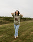 Rebel Blue Ranch Mustangs Tee. A woman wears a mineral wash olive green boxy oversized Rebel Blue Ranch tee with a horses design based on the cowboy romance book series by Lyla Sage that includes Done and Dusted, Swift and Saddled, Lost and Lassoed, and Wild and Wrangled. Meadowlark bookish merch. Lyla Sage merch.