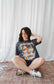 Person wearing a graphic t-shirt sitting on the floor against a white curtain. Striped oversized boxy Gothic Fantasy Tee / t-shirt. For book lovers of the romantasy genre. 