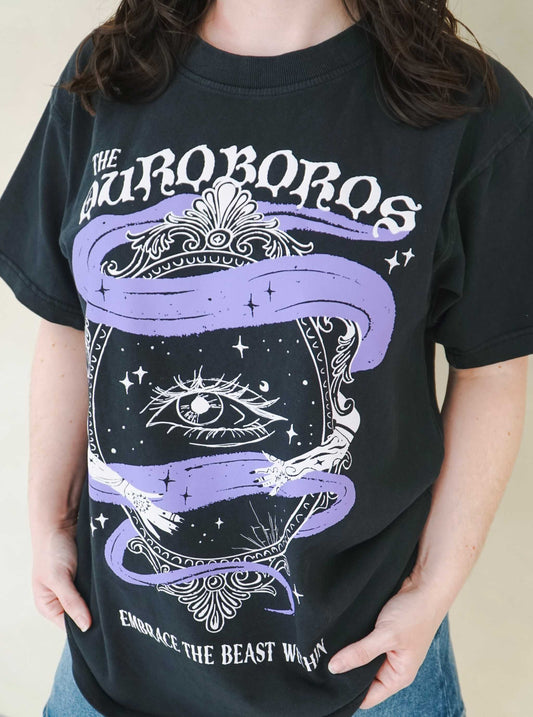 Person wearing a black t-shirt with 'The Ourororos' design featuring an eye, mirror, and purple mist. Inspired by the A Court of Thorns of Roses book series by Sarah J. Maas.