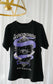 Black t-shirt with graphic design hanging on a white curtain background. A black graphic tee with 'The Ourororos' design featuring an eye, mirror, and purple mist. Inspired by the A Court of Thorns of Roses book series by Sarah J. Maas.