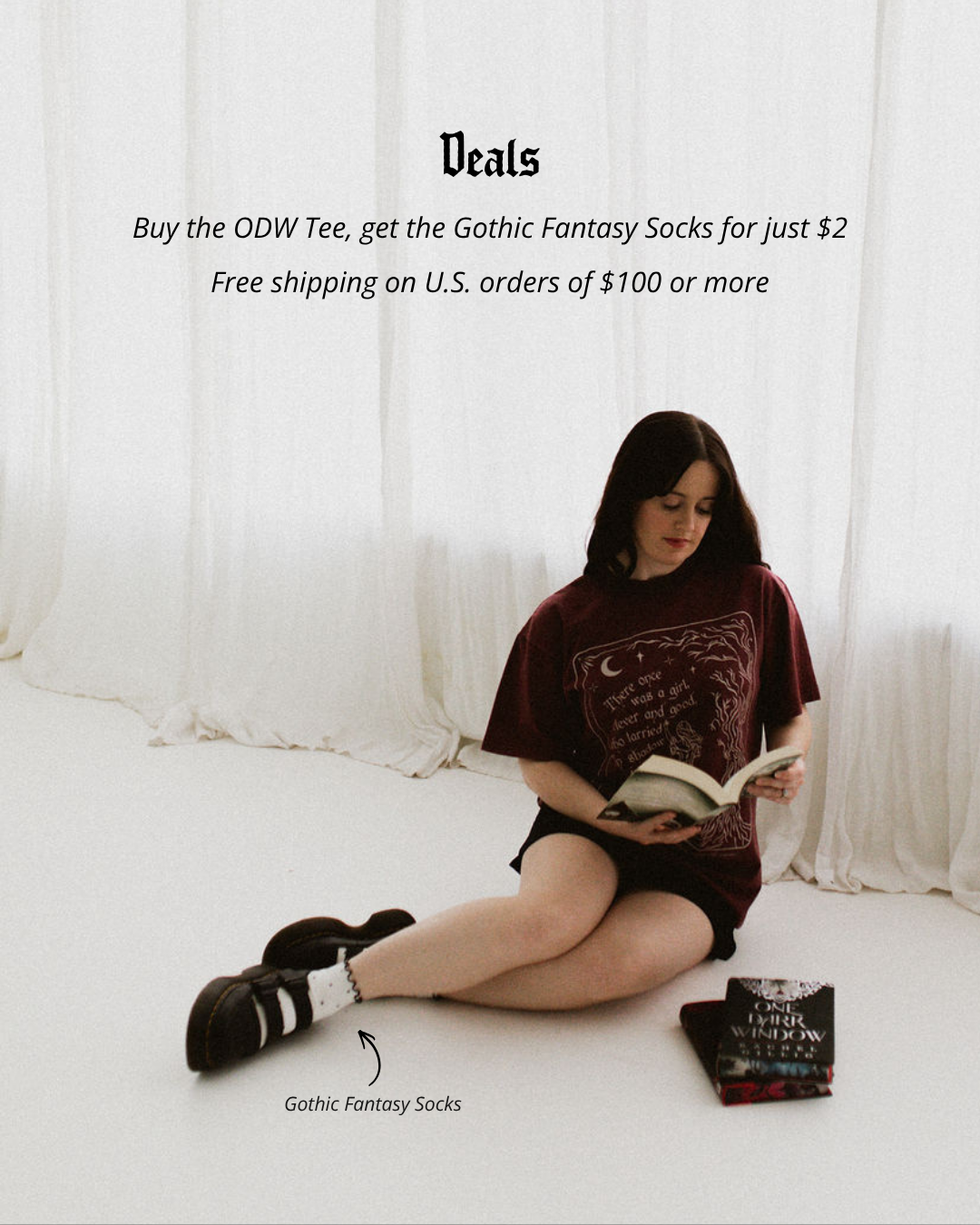 The One Dark Window Tee from Next Chapter is officially licensed by Rachel Gillig and inspired by the Shepherd King Duology. Next Chapter is an official retailer of Rachel Gillig licensed merchandise. This image shows a model wearing the One Dark Window Tee in the maroon color option.