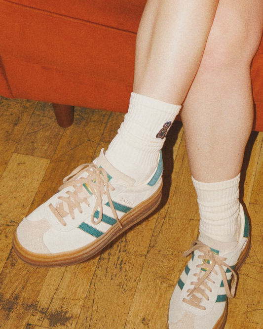 Ivory crew Book Bear Socks with embroidered bear patch worn with beige and green sneakers on wooden floor