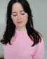 Woman wearing a cozy pink Reader Knit Sweater for book lovers with 'reader' embroidered along the collar. 