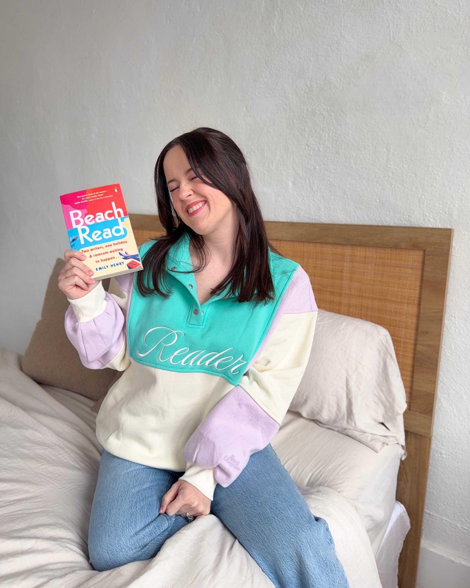 The Reader Colorblock Pullover from Next Chapter is oversized, with a quarter button-up style. This variant is lilac, teal, and ivory and has the word 'Reader' embroidered across the front. Next Chapter offers high quality bookish merch and apparel. 