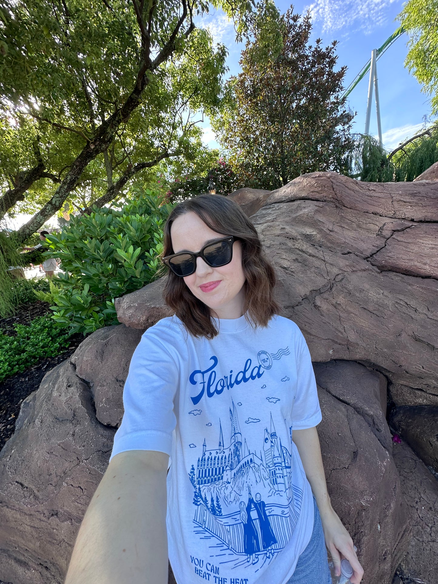 A woman wears a t-shirt that depicts the Wizarding World of Harry Potter theme park. The t-shirt also references Taylor Swift's song "Florida!!!" as well as the opening date of the park. 