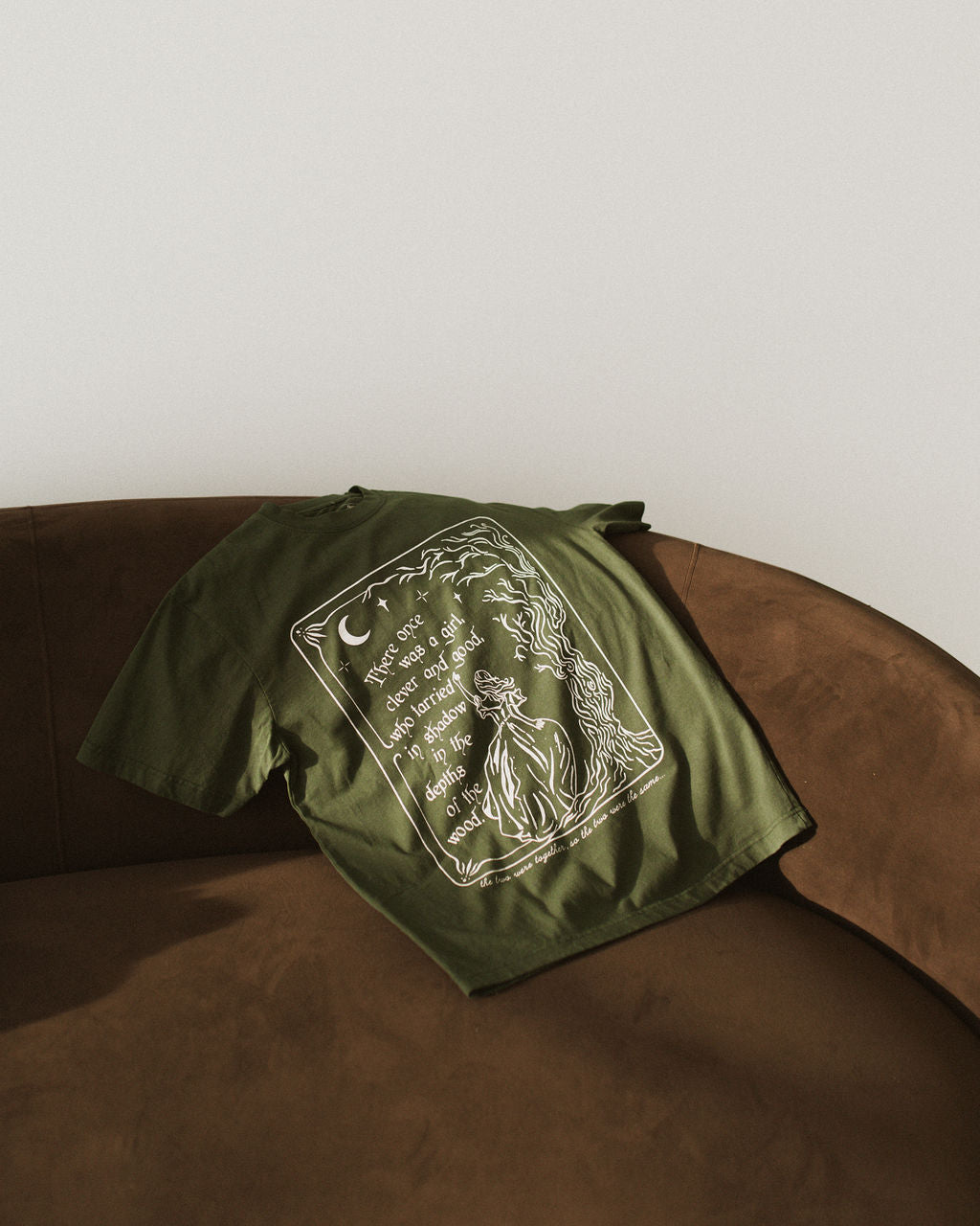 The One Dark Window Tee from Next Chapter is officially licensed by Rachel Gillig and inspired by the Shepherd King Duology. Next Chapter is an official retailer of Rachel Gillig licensed merchandise. This image shows the One Dark Window Tee in the green color option.