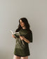The One Dark Window Tee from Next Chapter is officially licensed by Rachel Gillig and inspired by the Shepherd King Duology. Next Chapter is an official retailer of Rachel Gillig licensed merchandise. This image shows a model wearing the One Dark Window Tee in the green color option.