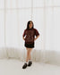 The One Dark Window Tee from Next Chapter is officially licensed by Rachel Gillig and inspired by the Shepherd King Duology. Next Chapter is an official retailer of Rachel Gillig licensed merchandise. This image shows a model wearing the One Dark Window Tee in the maroon color option.