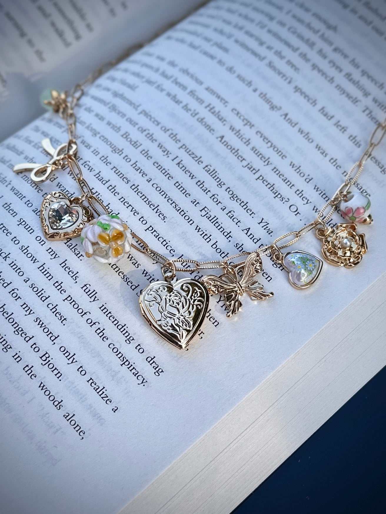 Gold romantasy charm necklace with charms on an open book