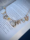 Gold romantasy charm necklace with charms on an open book