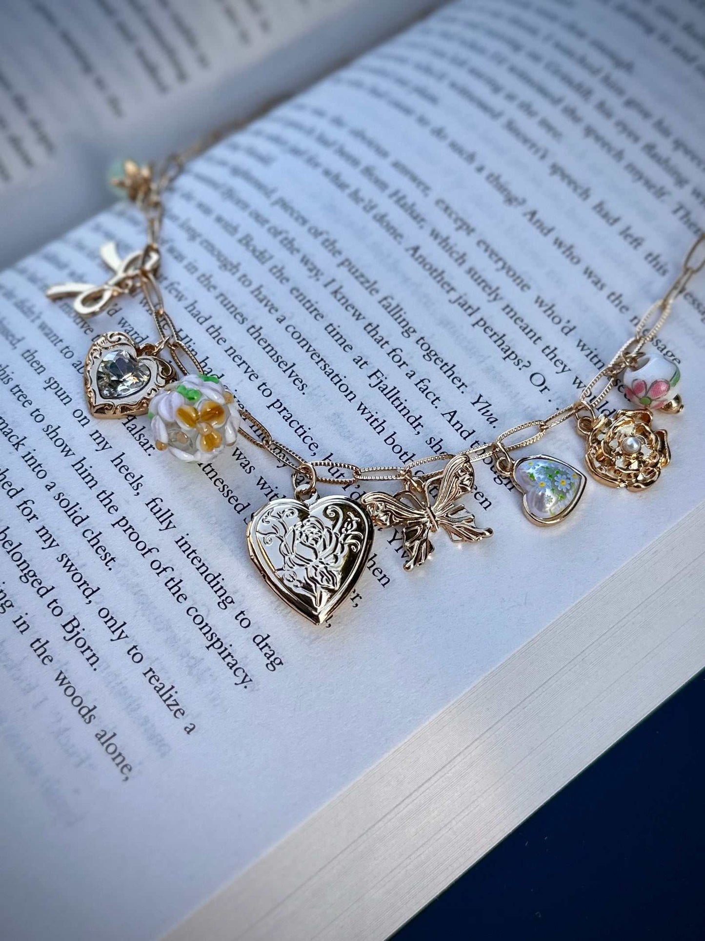 Gold romantasy charm necklace with charms on an open book