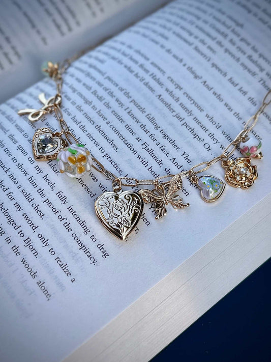 Gold romantasy charm necklace with charms on an open book