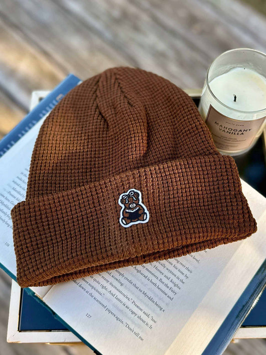 Brown book bear beanie hat with a bookish bear emblem holding a book.