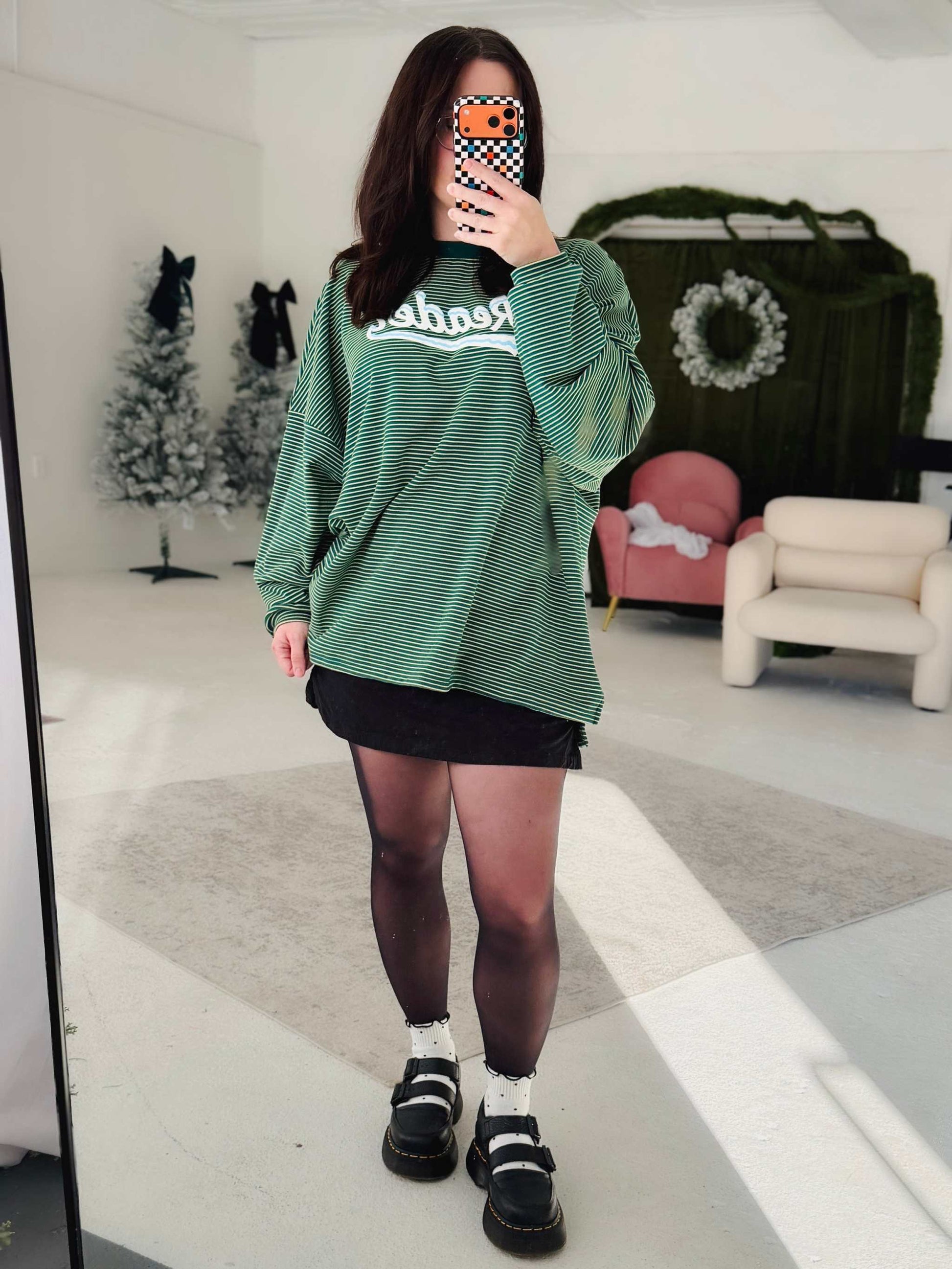 A woman wearing a green Snowy Reader Striped Oversized Top with snowcapped 'Reader' text.