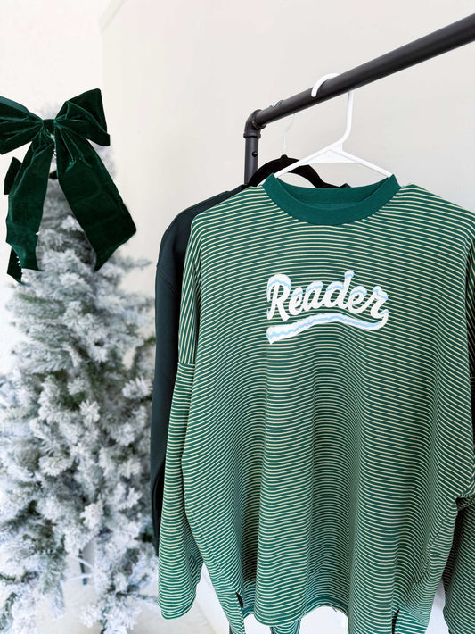 A green Snowy Reader Striped Oversized Top with snowcapped 'Reader' text on a hanger against a white wall.