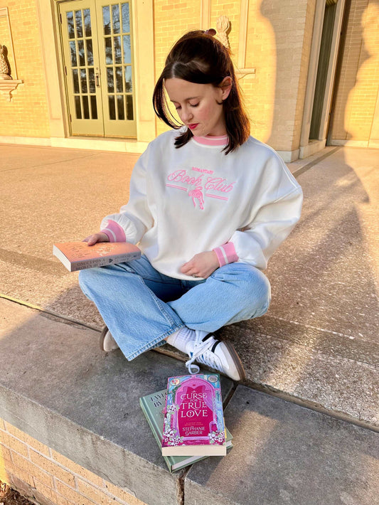 Romantasy Book Club Crewneck. Embroidered sweatshirt with a stylish pink trim collar and sleeves. Book merch for lovers of the romance and fantasy bookish genres.