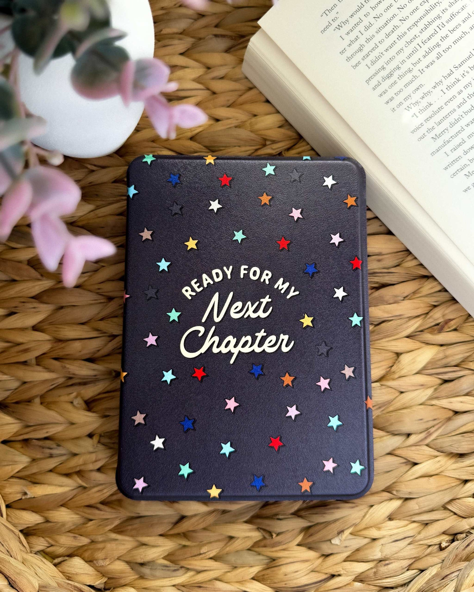 The Next Chapter Kindle Case is bold, vibrant, and covered in colorful stars! It features a cute bookish saying 'Ready For My Next Chapter' on the front and has a hand strap with magnetic backing.