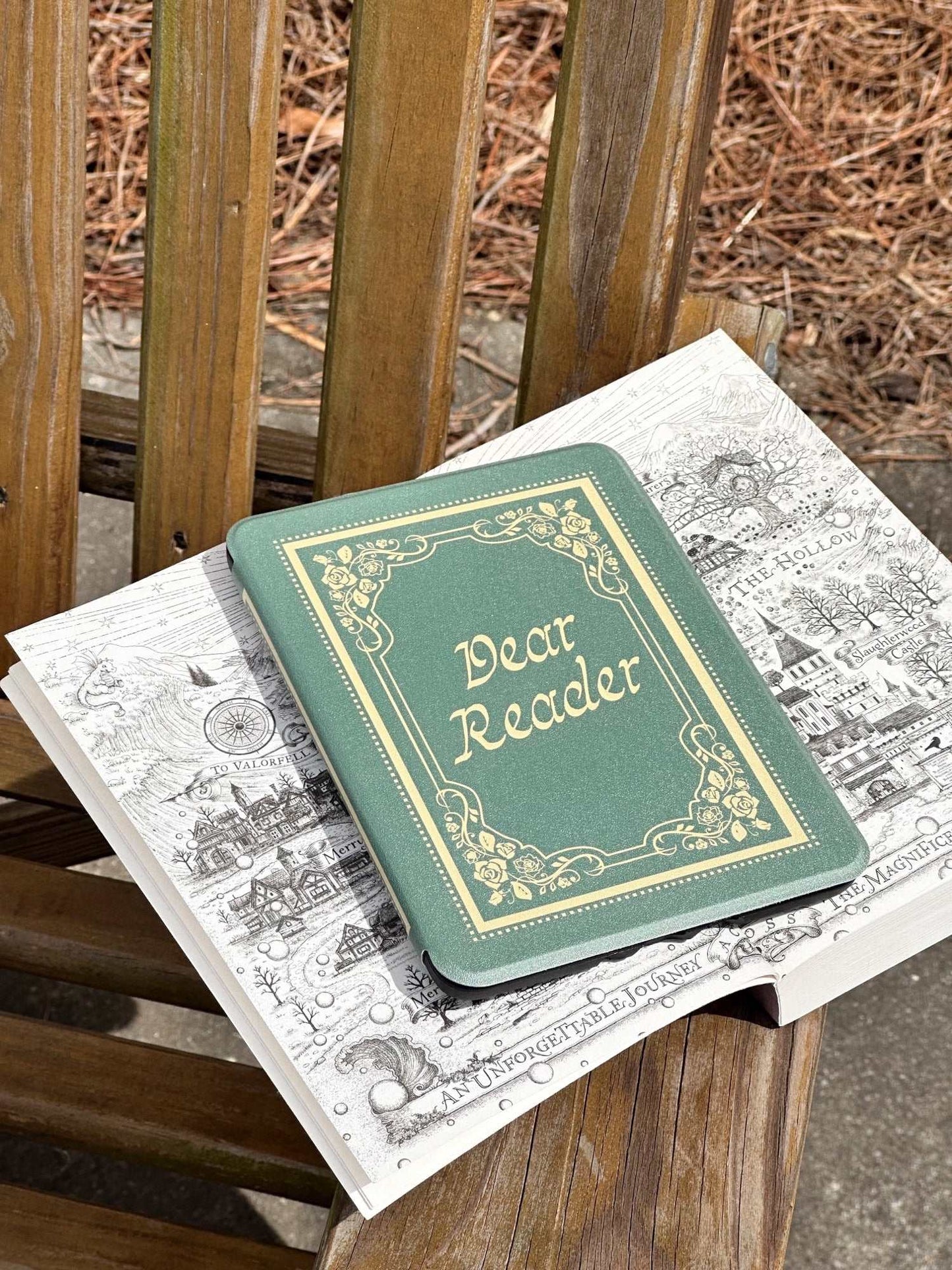 Small green kindle case that looks like a book with 'Dear Reader' on an open book. The Dear Reader Kindle case from Next Chapter is inspired by the Taylor Swift song 'Dear Reader.' The case has a vintage and soft feminine style and looks like a real book.