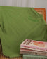 Cozy green Reader Knit Sweater for book lovers draped over a chair with books stacked on it against a white curtain background. The word 'reader' is embroidered along the collar.