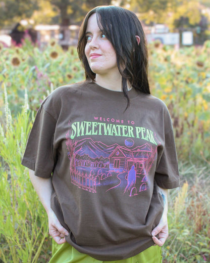 A woman wearing the Sweetwater Peak Tee from Next Chapter, inspired by the book Free Falling by Lyla Sage
