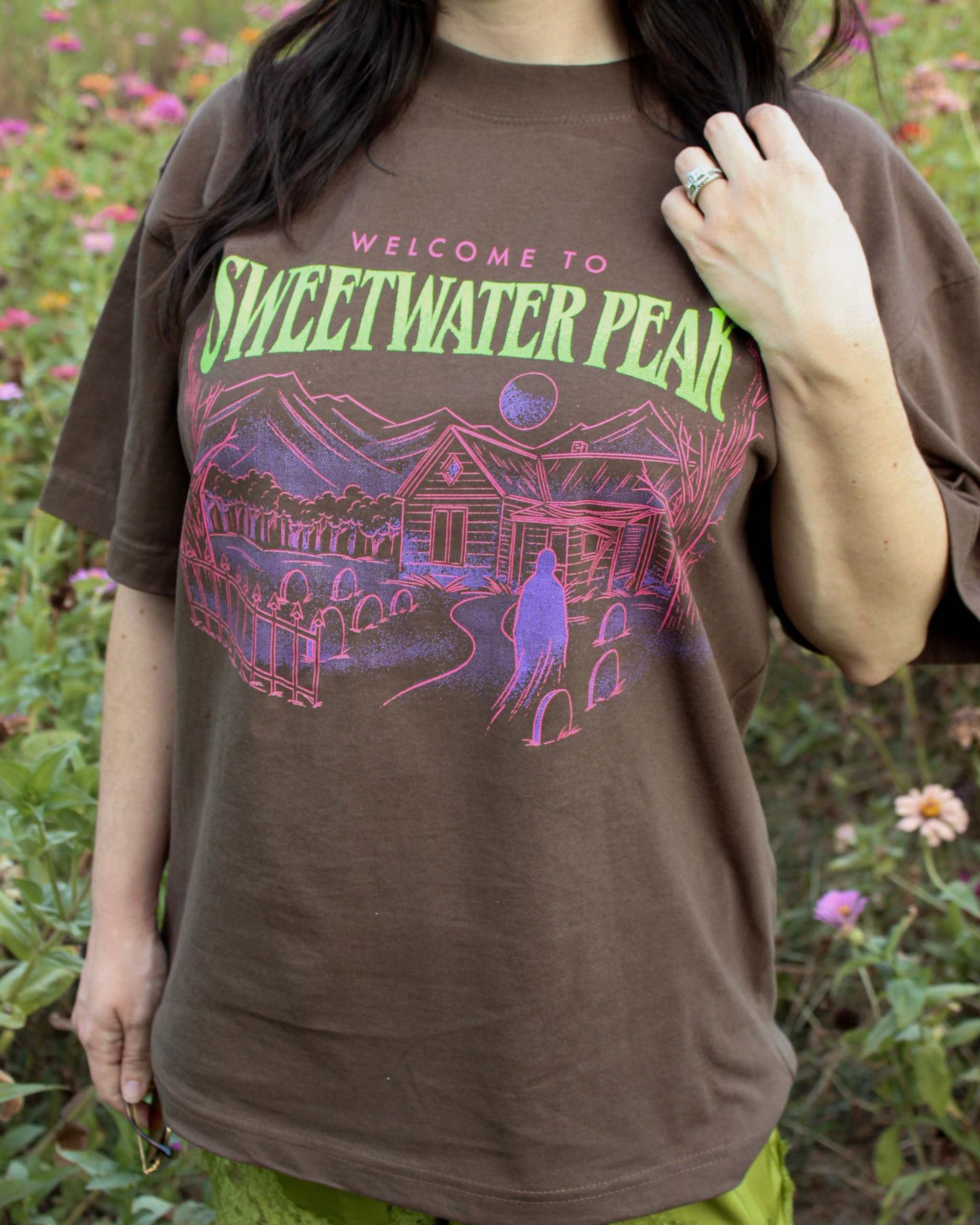 A woman wearing the Sweetwater Peak Tee from Next Chapter, inspired by the book Free Falling by Lyla Sage