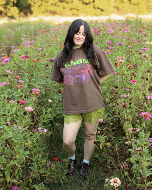 A woman wearing the Sweetwater Peak Tee from Next Chapter, inspired by the book Free Falling by Lyla Sage