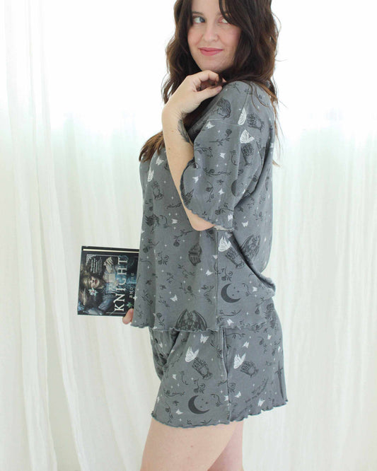A woman wearing the knight and the moth lounge set from Next Chapter. This is a cozy bookish pajama set for fantasy book lovers, inspired by The Knight and the Moth.