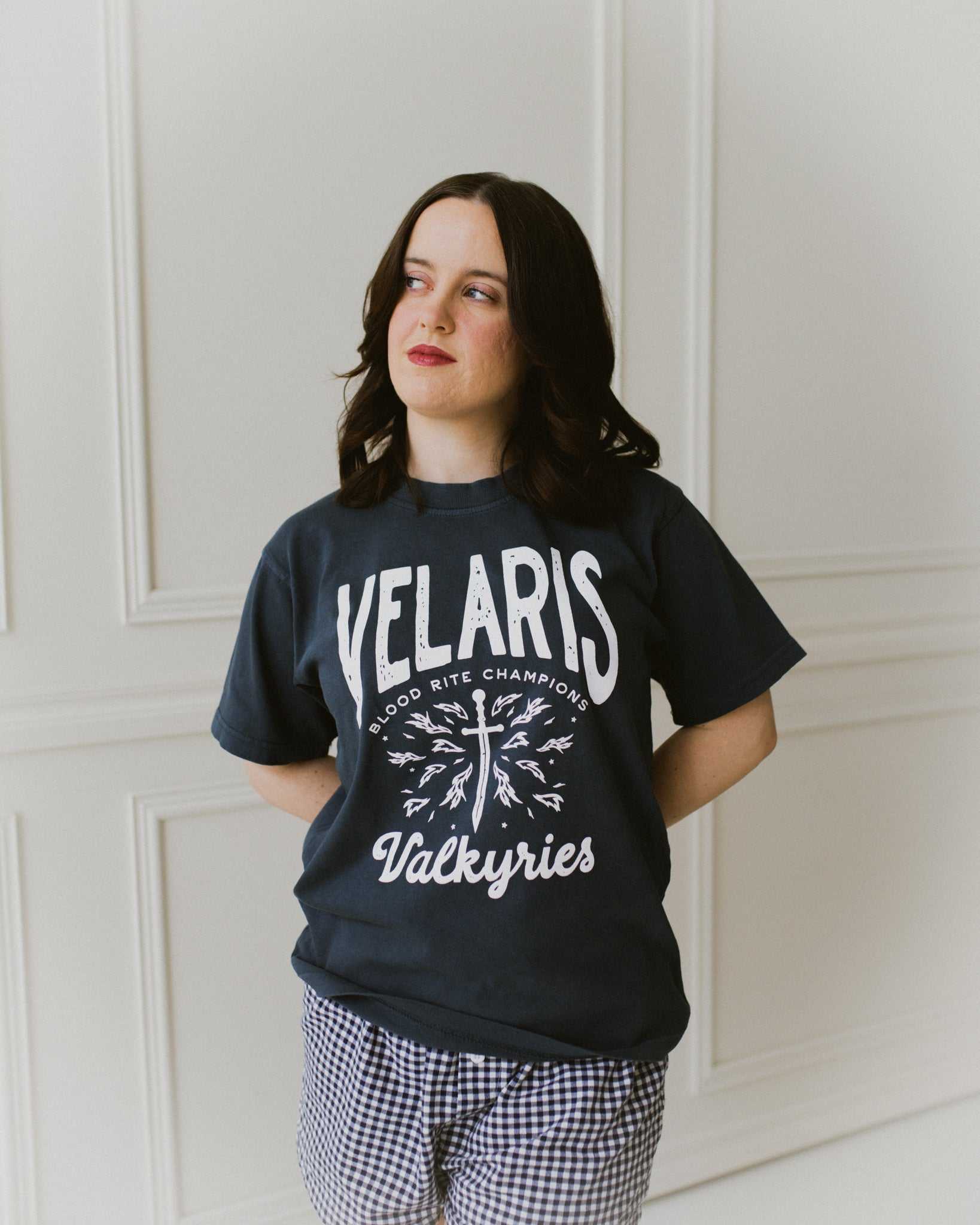 Velaris Valkyries tee featuring a deep navy fabric and white, screen printed design. From A Court of Silver Flames. Officially licensed by Sarah J. Maas. 