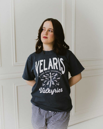 Velaris Valkyries tee featuring a deep navy fabric and white, screen printed design. From A Court of Silver Flames. Officially licensed by Sarah J. Maas. 